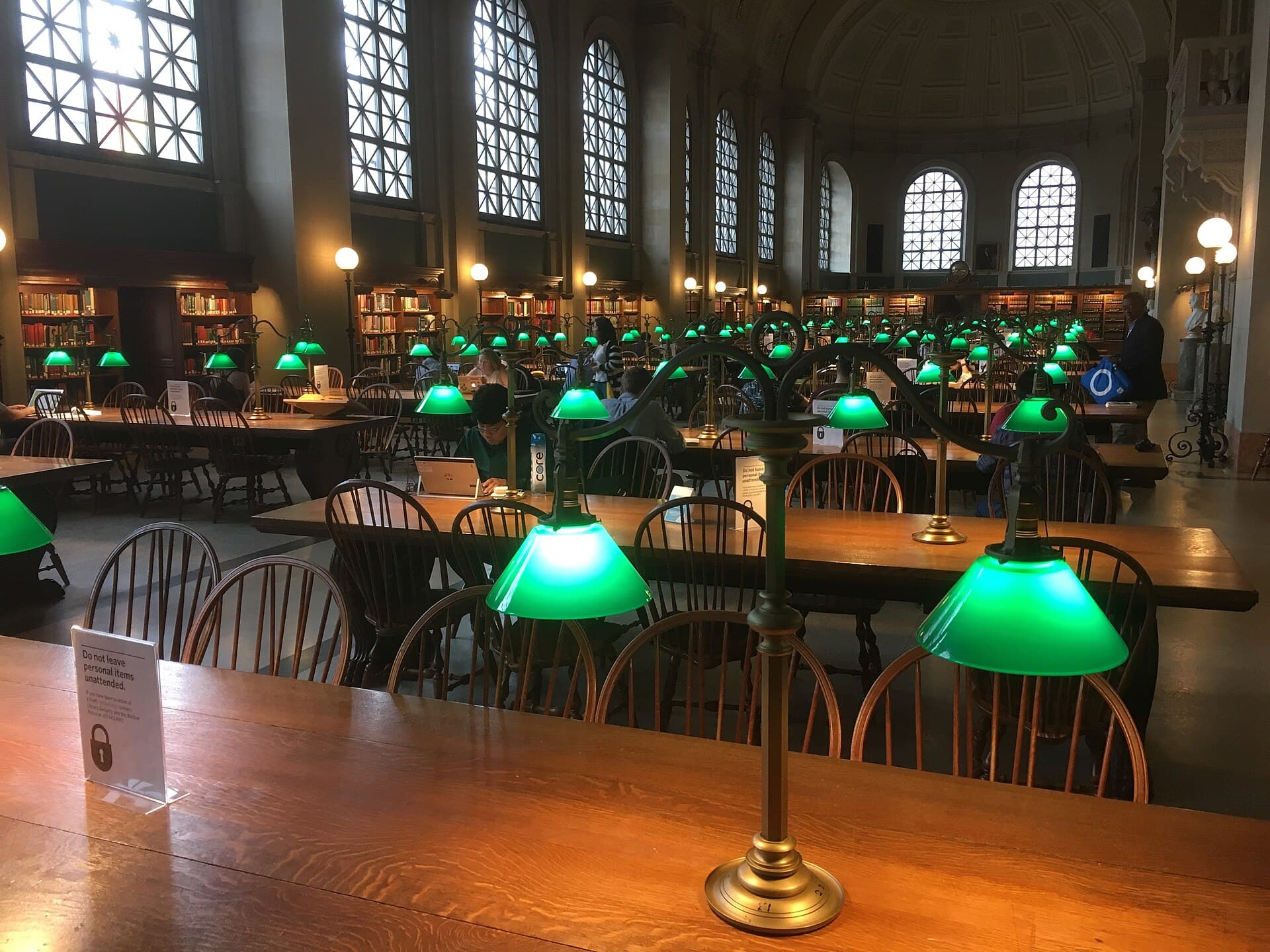Long wooden tables with green reading lamps in the Boston Public Library’s main reading room