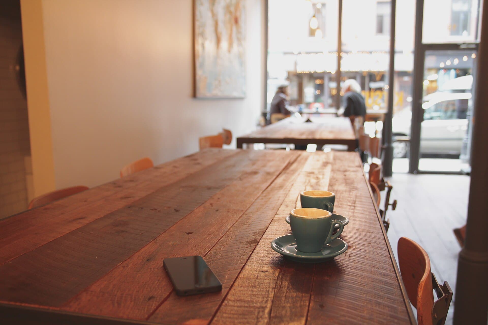 Two cups of coffee on a long wooden café table
