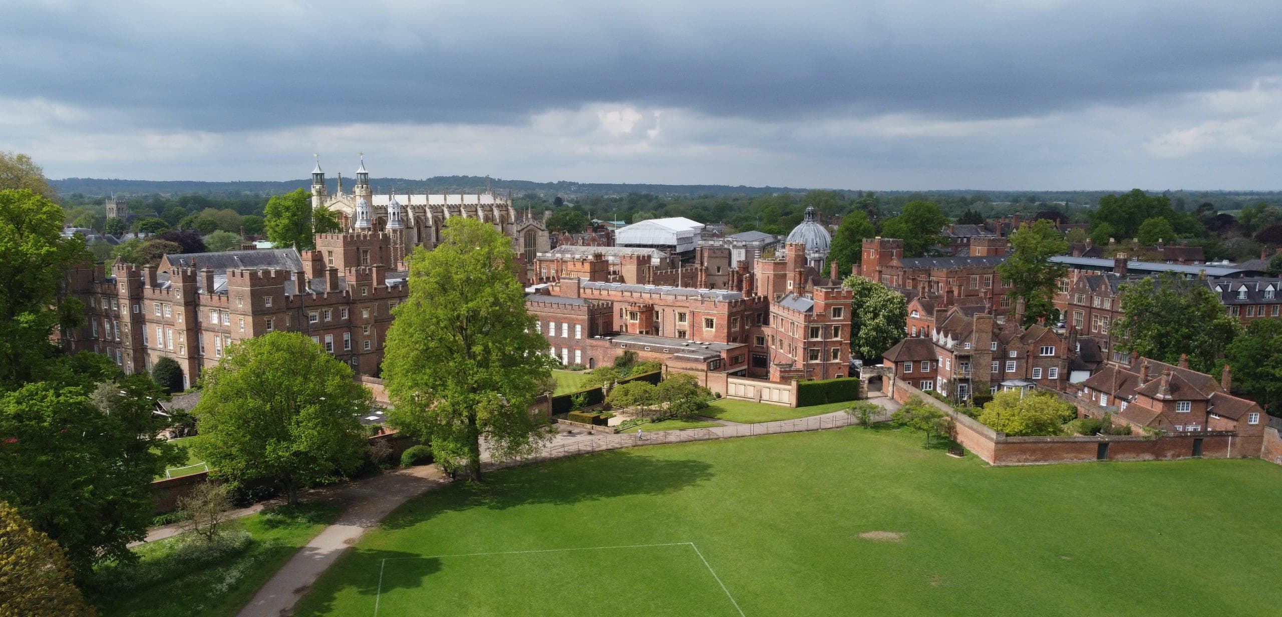 Eton College from the air, its red-brick buildings and chapel beyond a wide green playing field