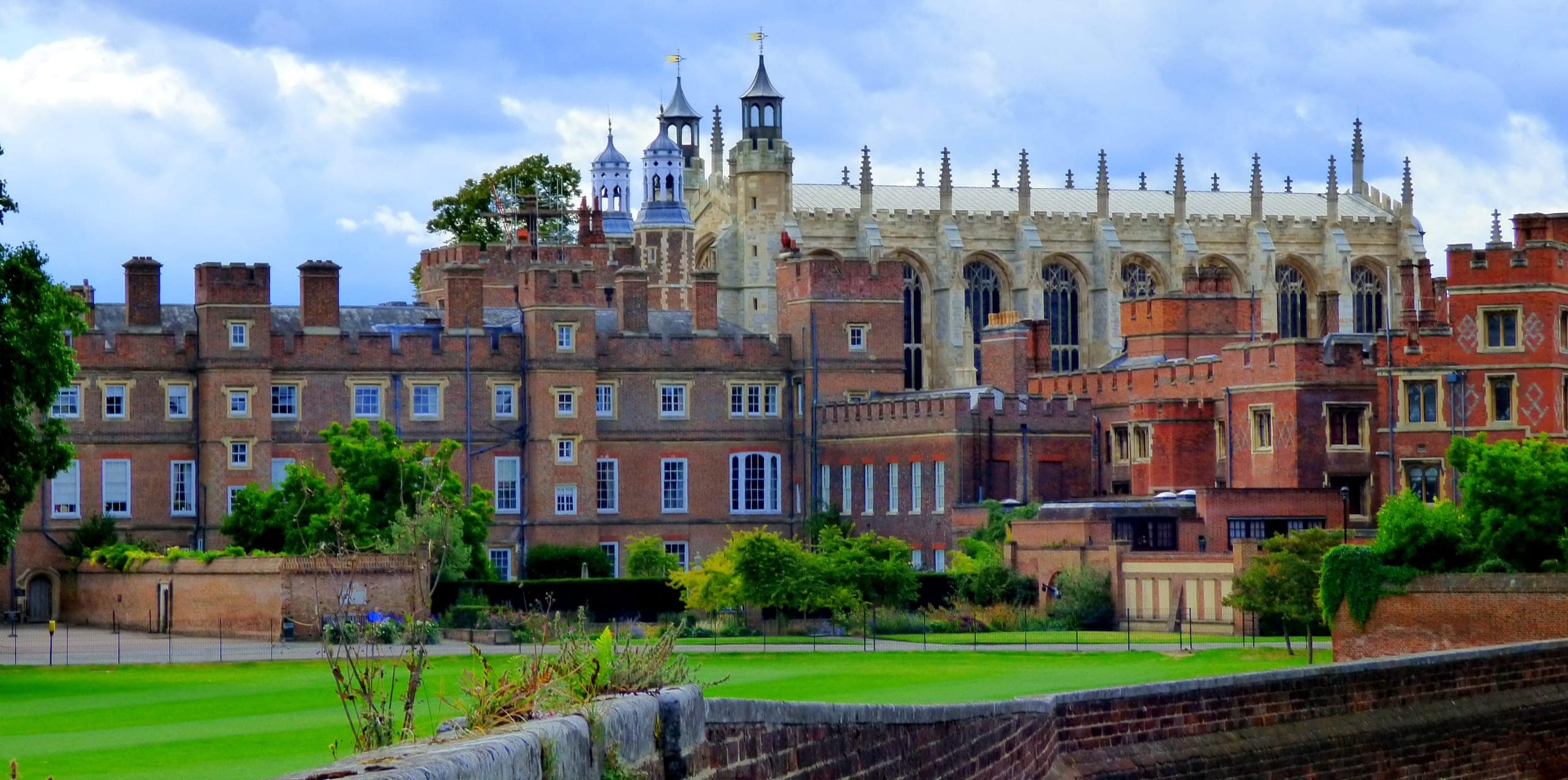 Eton College’s red-brick buildings, with the pinnacles and cupolas of the chapel behind, seen across a lawn and a low brick wall