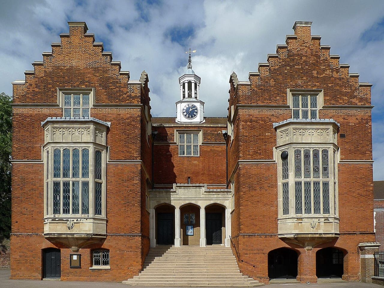 The red-brick Old Schools at Harrow, with stepped gables, a small clock tower, and stone steps