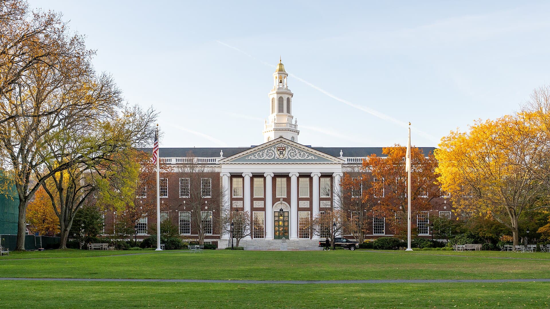 Baker Library at Harvard Business School, a brick building with a white bell tower, framed by autumn trees