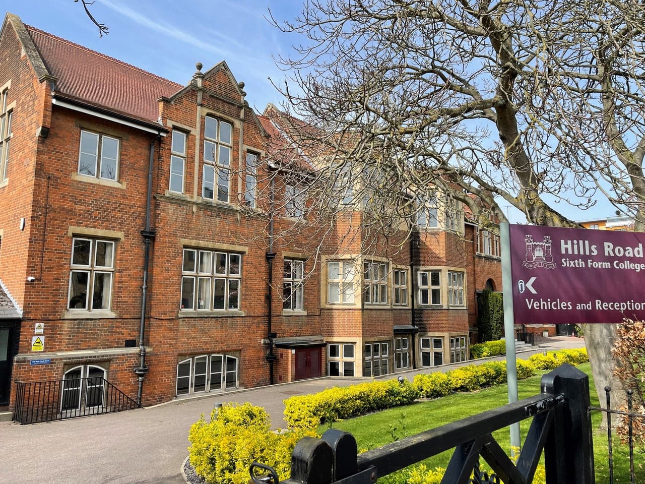 The red-brick front of Hills Road Sixth Form College in Cambridge, behind a yellow hedge