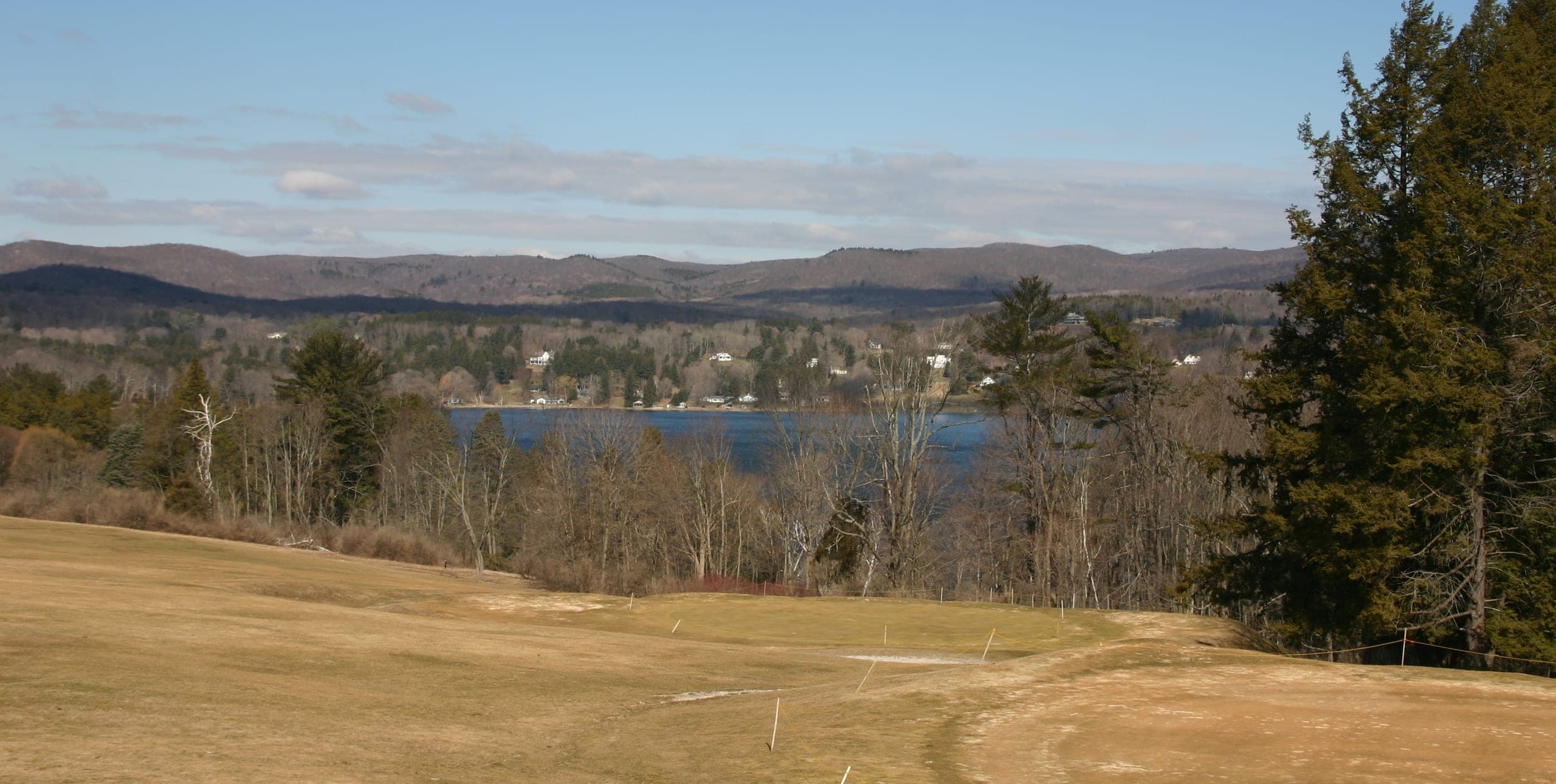 Lake Wononscopomuc and the Litchfield Hills seen from the Hotchkiss grounds in early spring, past a sloping field and bare trees