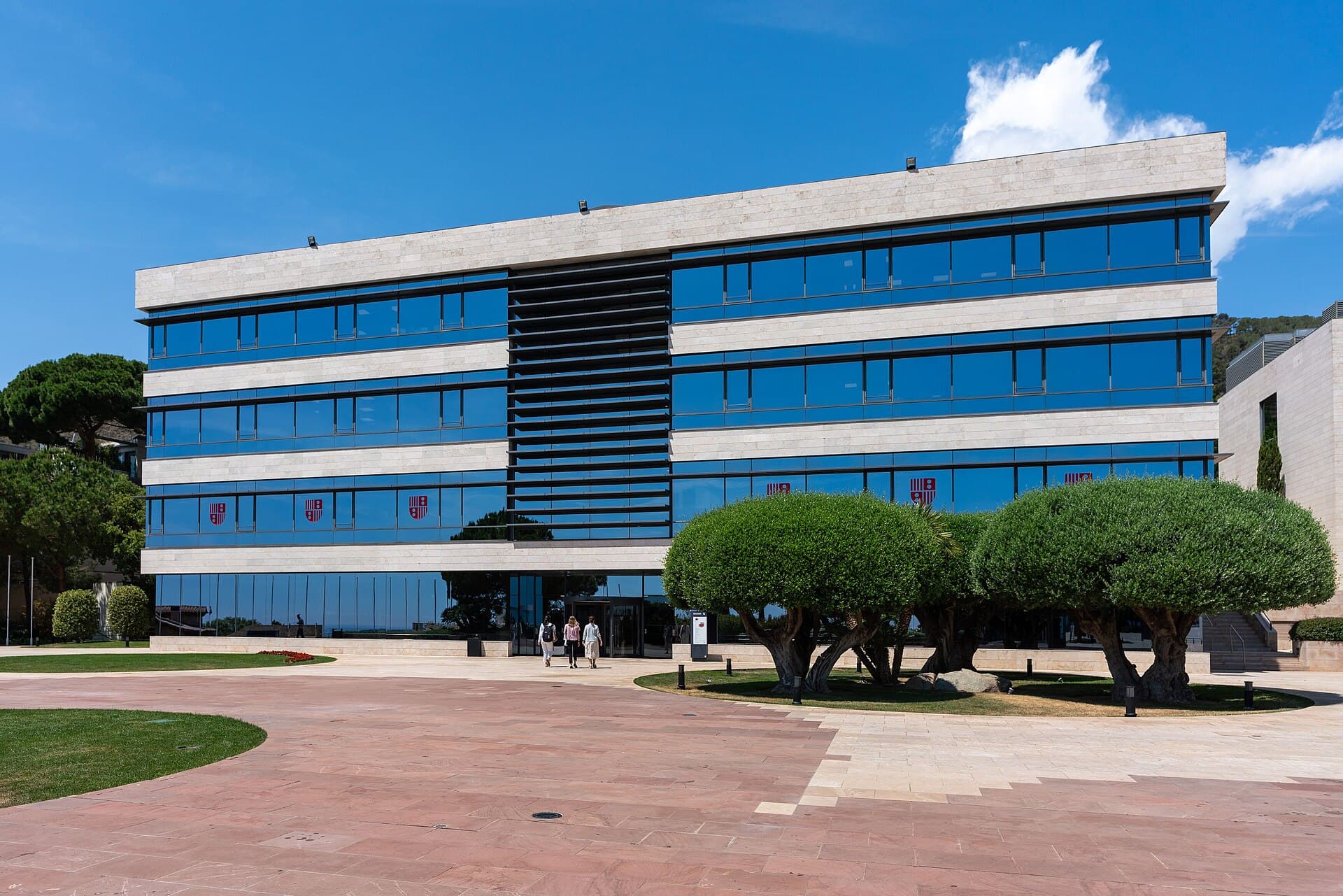A glass-fronted building and sculpted trees on IESE’s Barcelona campus
