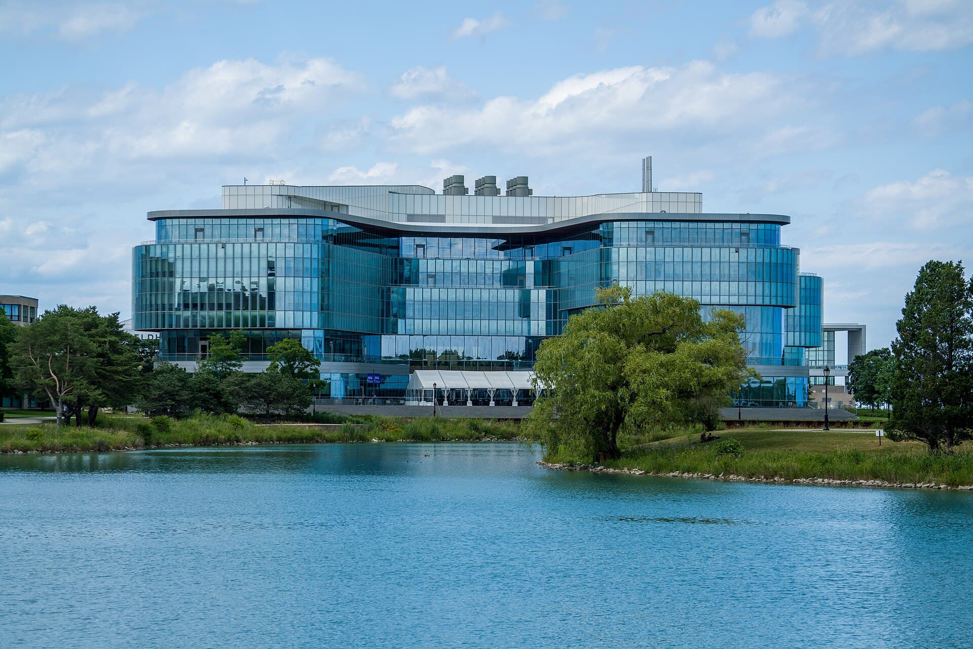The glass Kellogg Global Hub at Northwestern University beside a lagoon