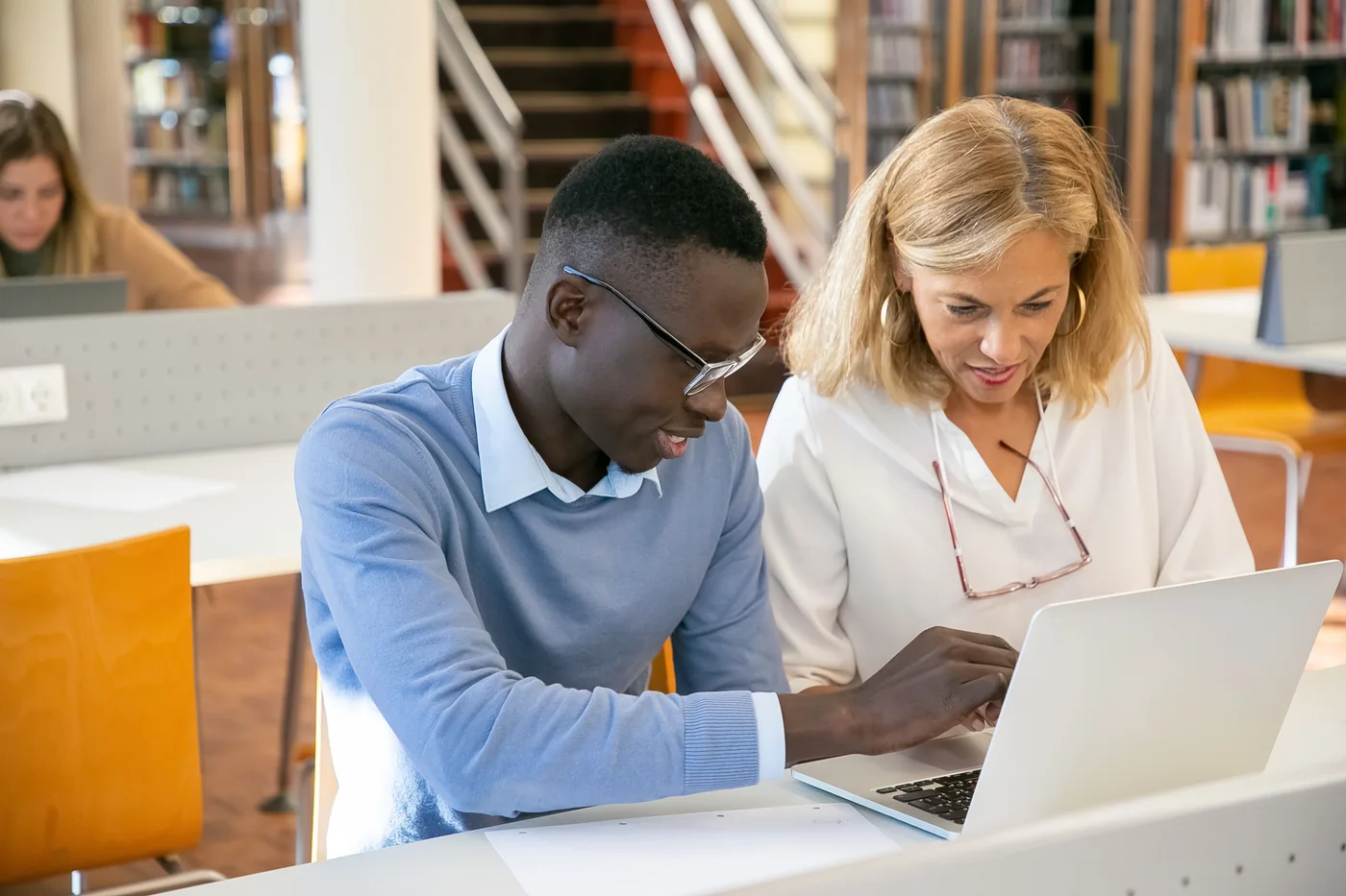 Tutor helping a student work through material on a laptop.