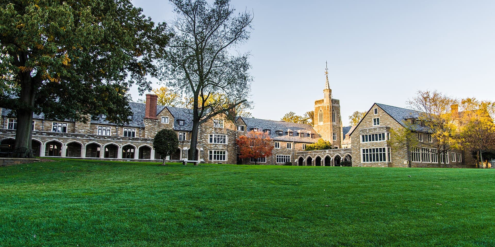 Stone buildings and a bell tower beyond the front lawn at St. Andrew’s School in Delaware